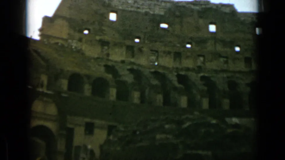 Wider 1962 8mm view inside the Rome Colosseum, with multiple arches, weathered walls, and shadowed lower areas.