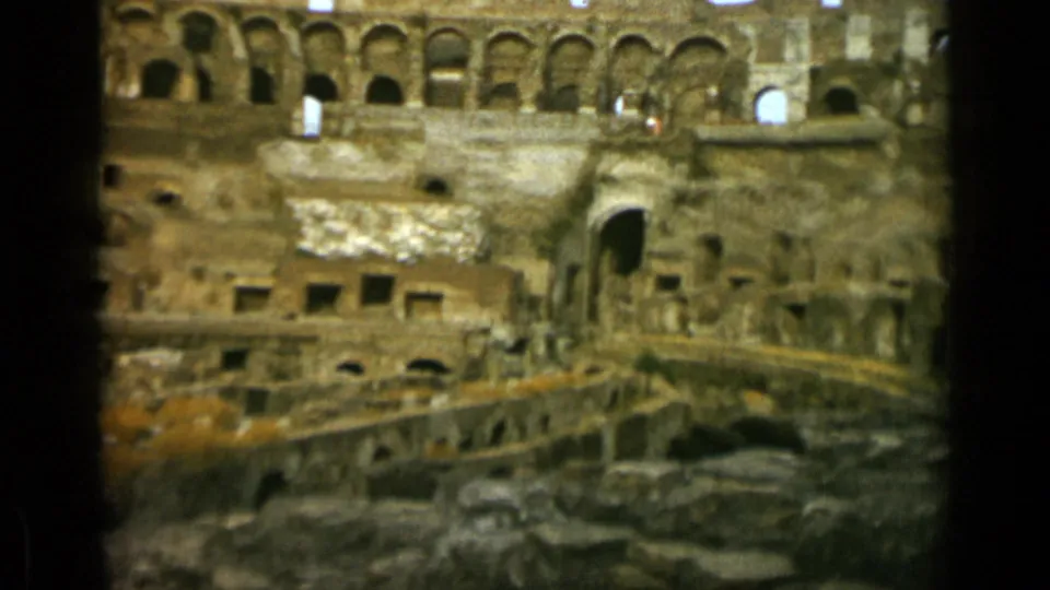 1962 Rome footage frame of the Colosseum interior with layered arches, worn wall surfaces, and exposed lower structures.