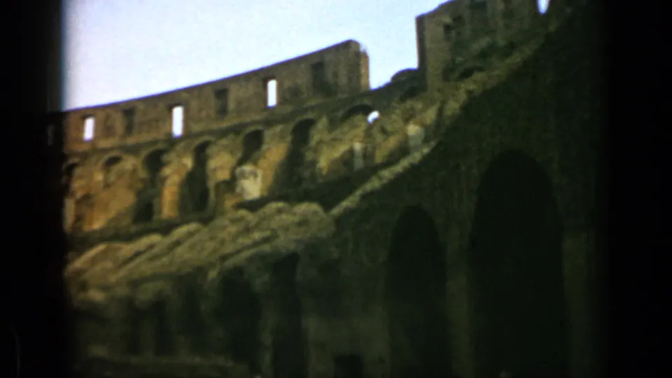 1962 8mm Rome travel footage showing a low-angle section of the Colosseum with weathered arches and dark openings.