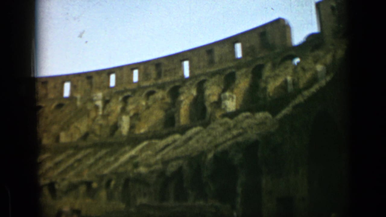 A Rome Colosseum view on 8mm film, with repeated upper openings and weathered stone layers across the frame.
