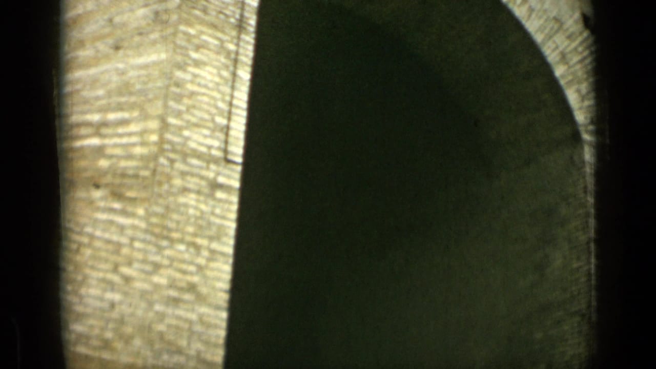 Tall arched masonry opening with bright stone texture and deep shadow.