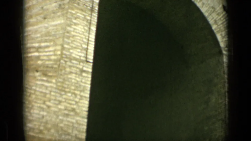 1962 Rome 8mm frame with a tall rounded arch, textured stone surface, and heavy shadow filling the opening.