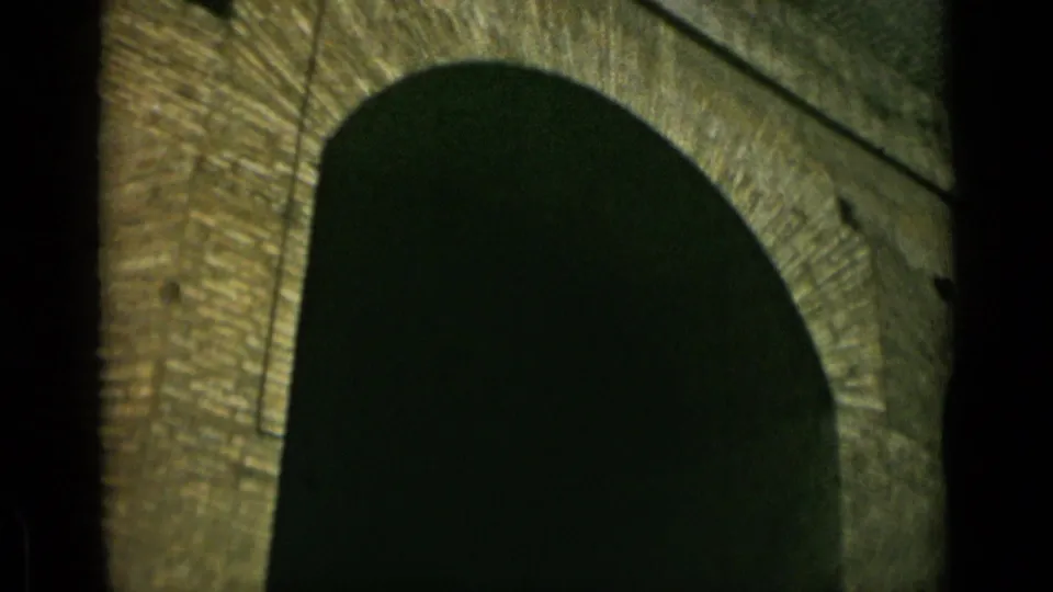 1962 Rome home-movie frame showing a lower angle on a rounded arch beneath weathered stone or brickwork.