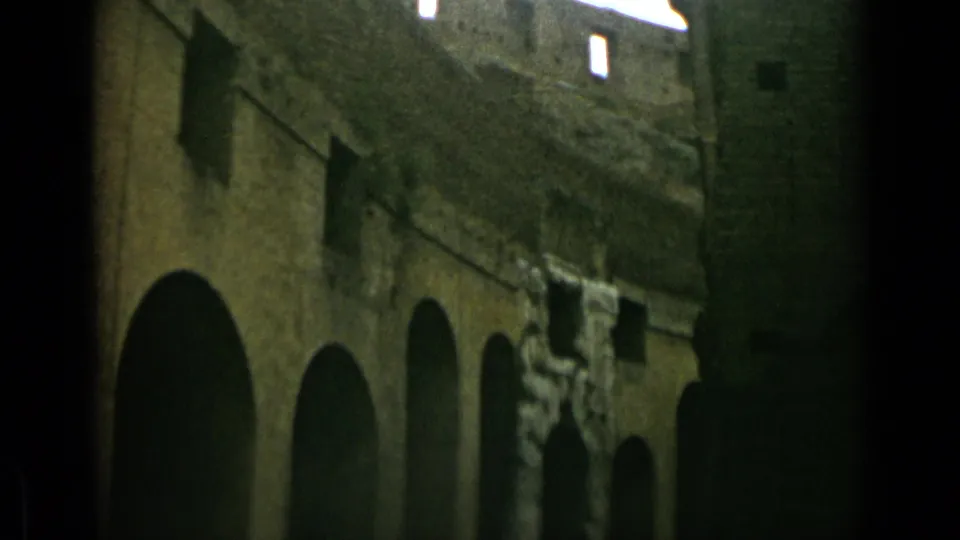 Low-angle 1962 view of Colosseum arches in Rome, with dim passageways, aged masonry, and bright sky through upper gaps.