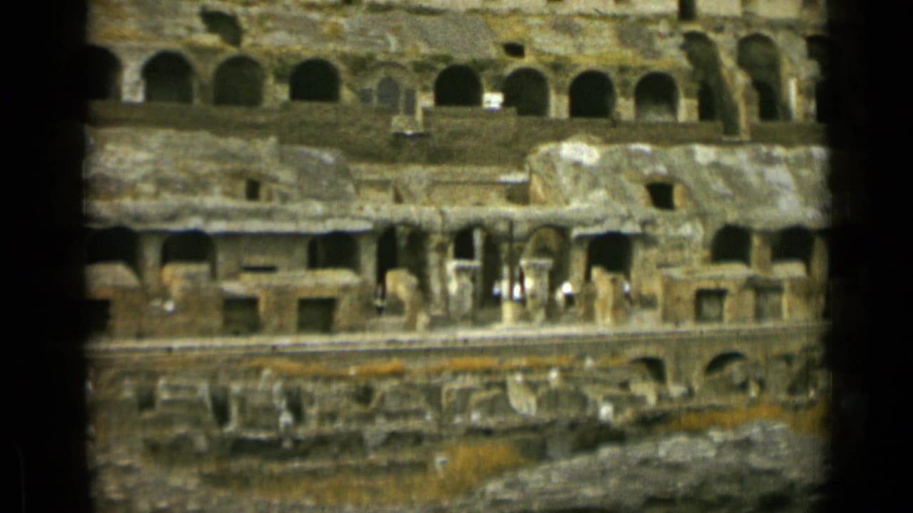 Arched stone levels of the Colosseum with dark film borders and small visitors below.