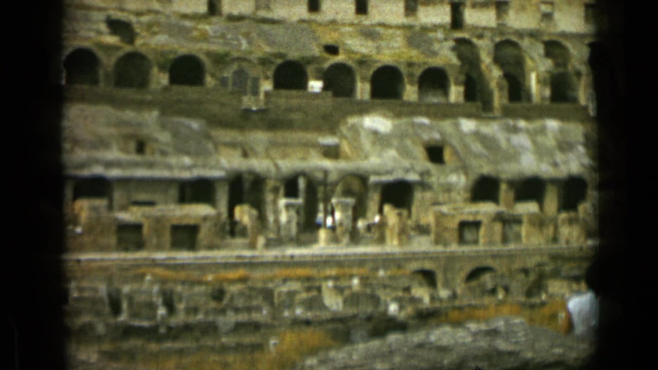 Colosseum interior tiers with arched openings, worn walls, and a partial visitor at the edge.