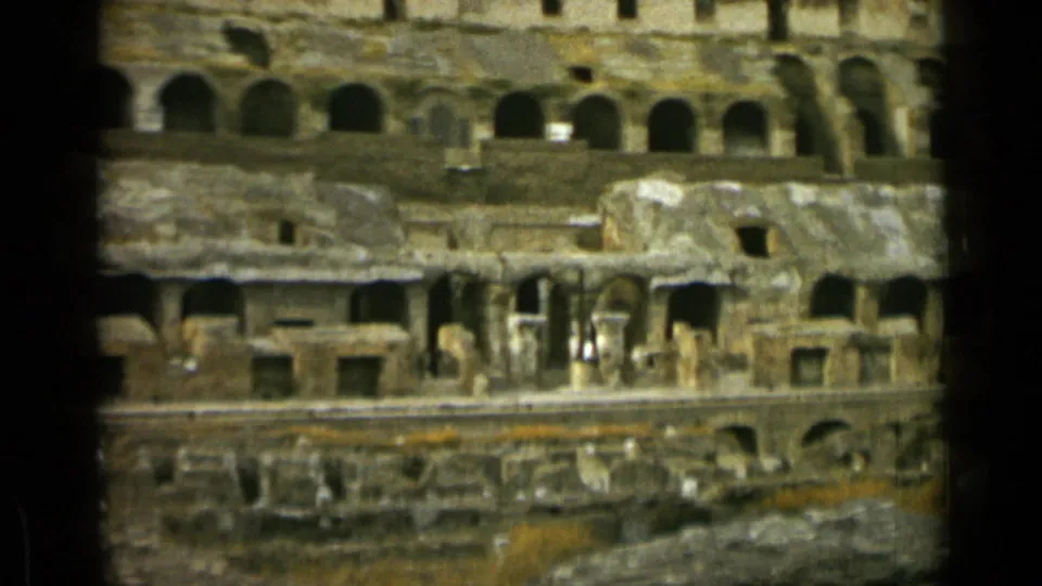 1962 Rome home-movie frame showing the Colosseum's arched interior levels, rough masonry, and lower ruin areas in faded color.