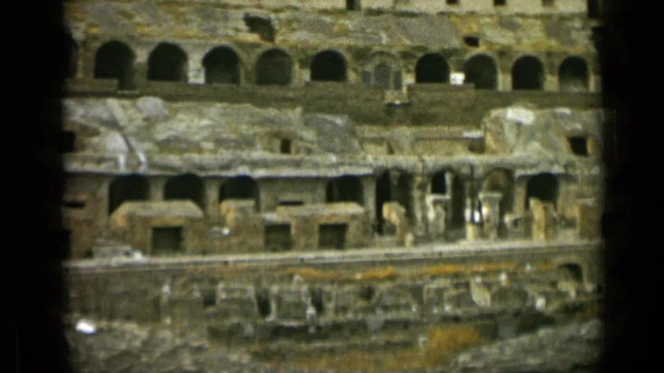 Rome 1962 8mm frame of the Colosseum interior, with layered stone arches, eroded surfaces, and shadowed film borders.