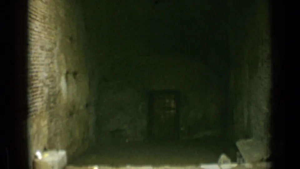 A dim interior passage or alcove appears between courtyard shots, with rough walls, a small window, and stone pieces on the floor.
