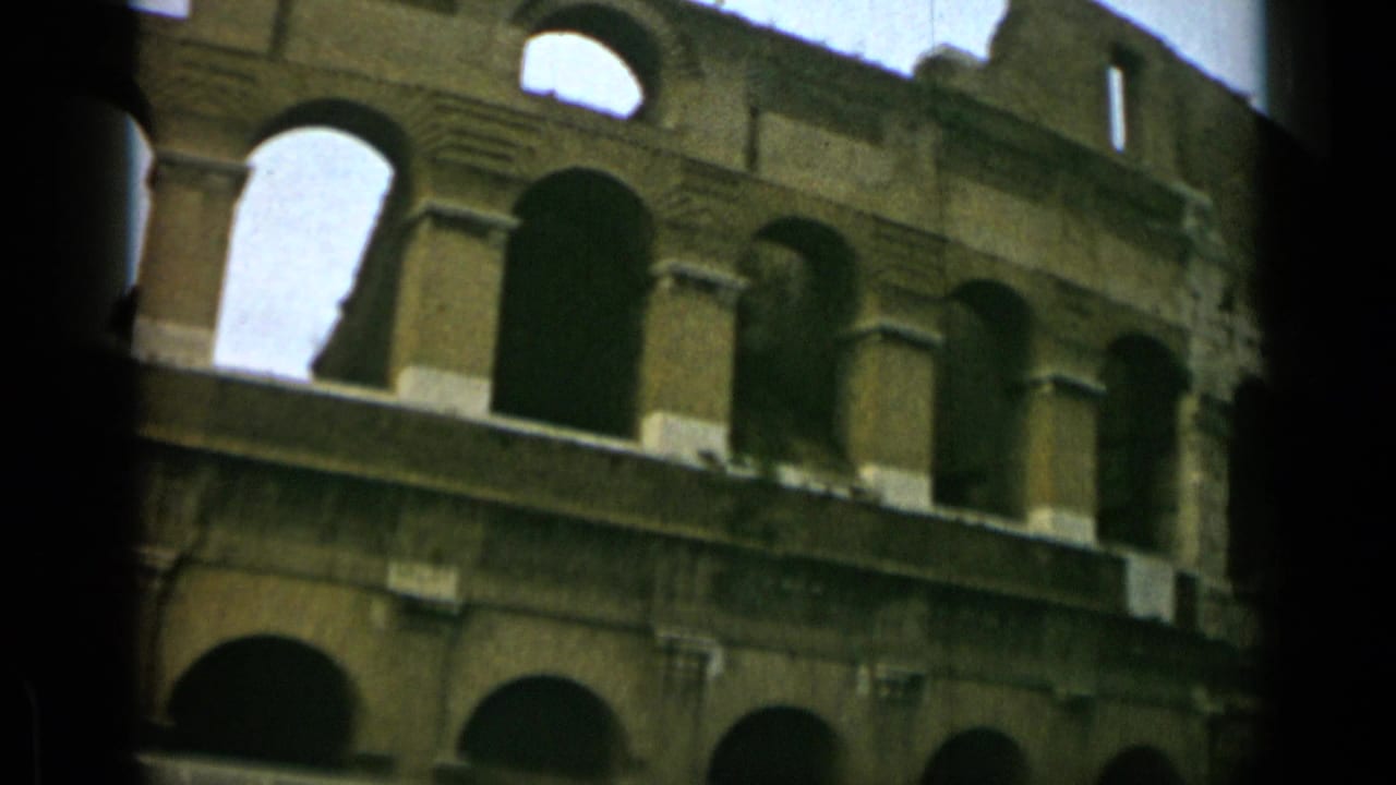 Angled view of the Colosseum facade with rows of arches and a dark vertical film edge.
