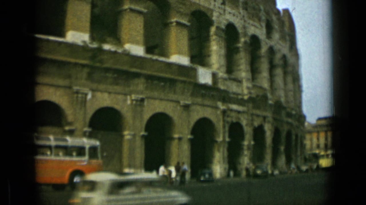 Colosseum arches with an orange-and-white bus, a small car, and pedestrians nearby.