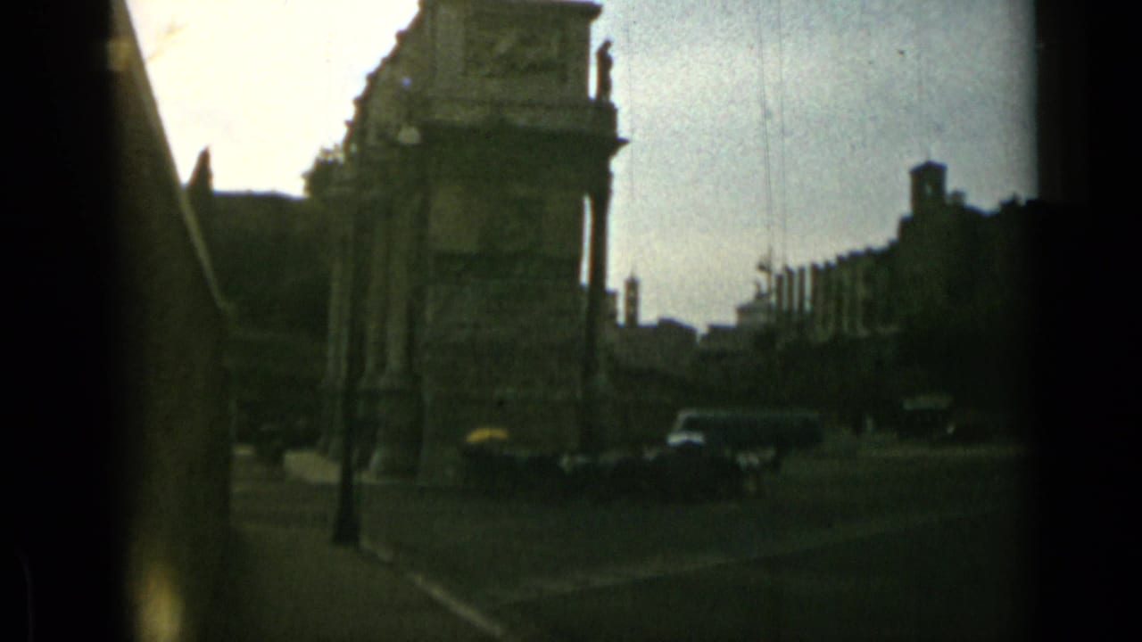 Historic stone structure beside a roadway with cars and trees.