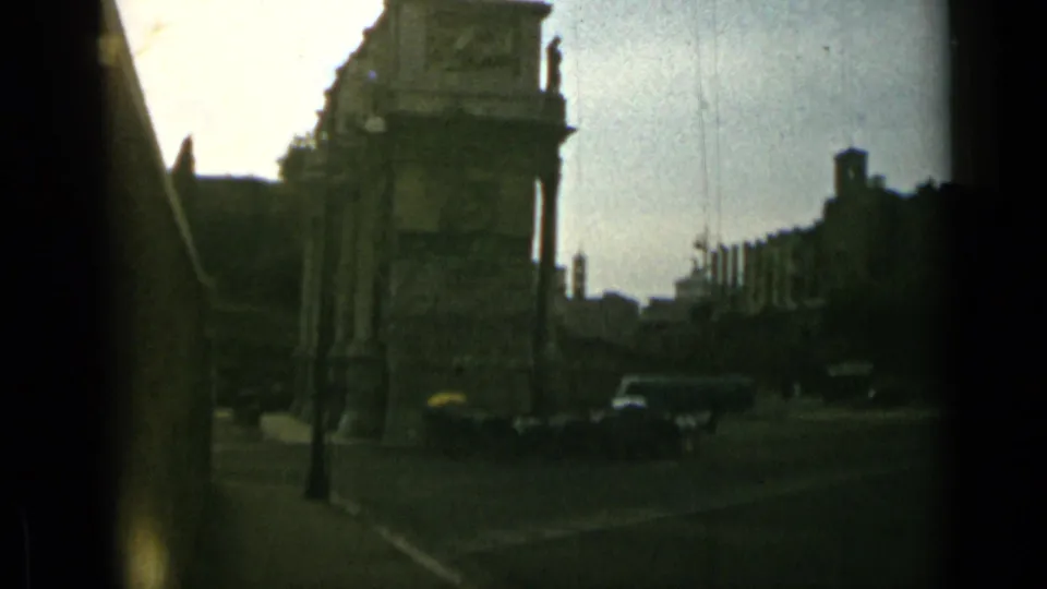Rome street scene with historic masonry, moving cars, roadside posts, trees, and soft 8mm exposure.