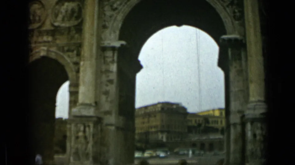1962 Rome cutaway through a stone arch, with carved architectural details, distant buildings, cars, and a small visible pedestrian.