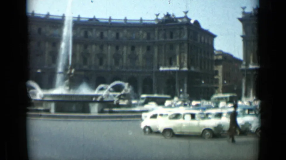 End frame of a 1962 Rome fountain scene with clustered cars, pedestrians, water jets, and a monumental building backdrop.