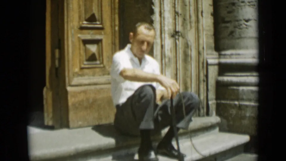 The Rome 1962 frame shows the man leaning forward on the steps, with a thin cord or leash visible near his shoes.