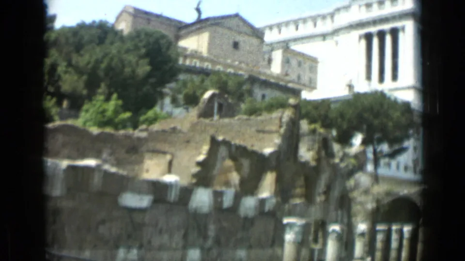 1962 Rome 8mm view of stone ruins and greenery with the bright white Altare della Patria facade rising in the background.