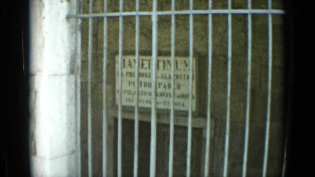 Latin stone plaque seen through vertical metal bars.