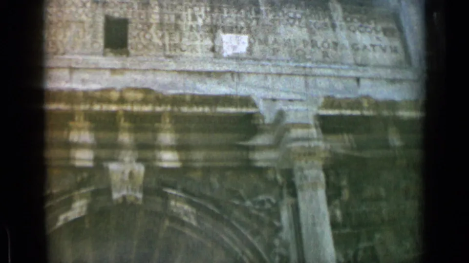 1962 8mm Rome close-up of the Arch of Constantine, with Latin lettering, projecting stone ledge, column capital, and shadowed arch opening.