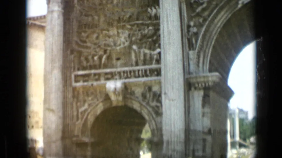 Rome 1962 home-movie still showing an arch opening, carved panel, column, and pale stone facade in soft 8mm color.