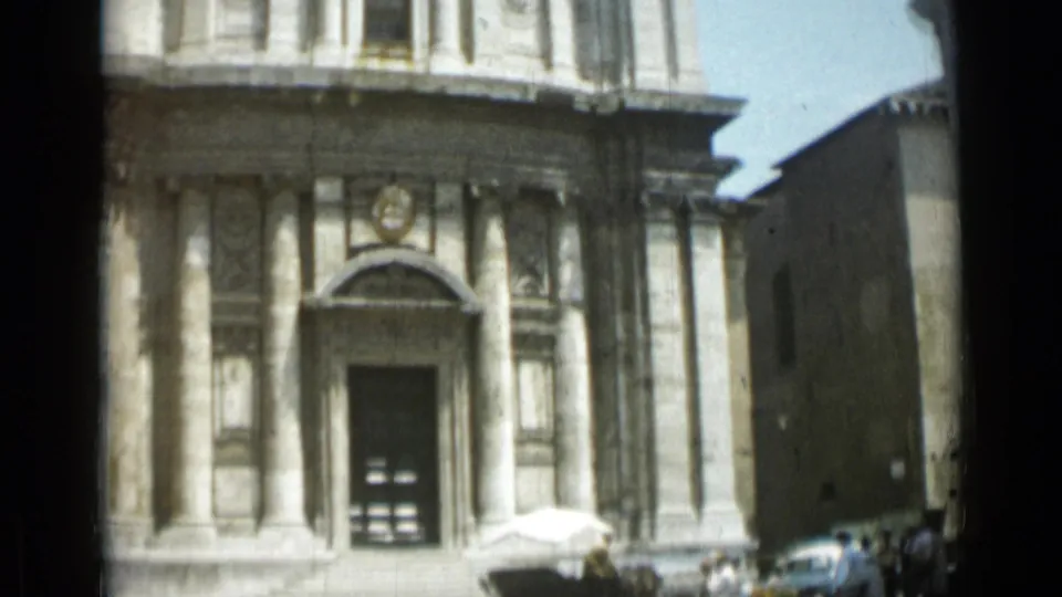 1962 Rome frame of the lower church facade, showing the arched entrance, front steps, adjacent wall, and cars at street level.