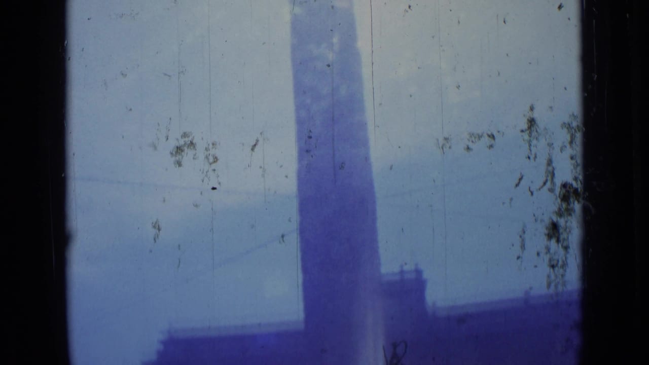 1962 Rome 8mm frame with a tall obelisk shape rising into bright sun glare, with soft blue sky and visible film wear.