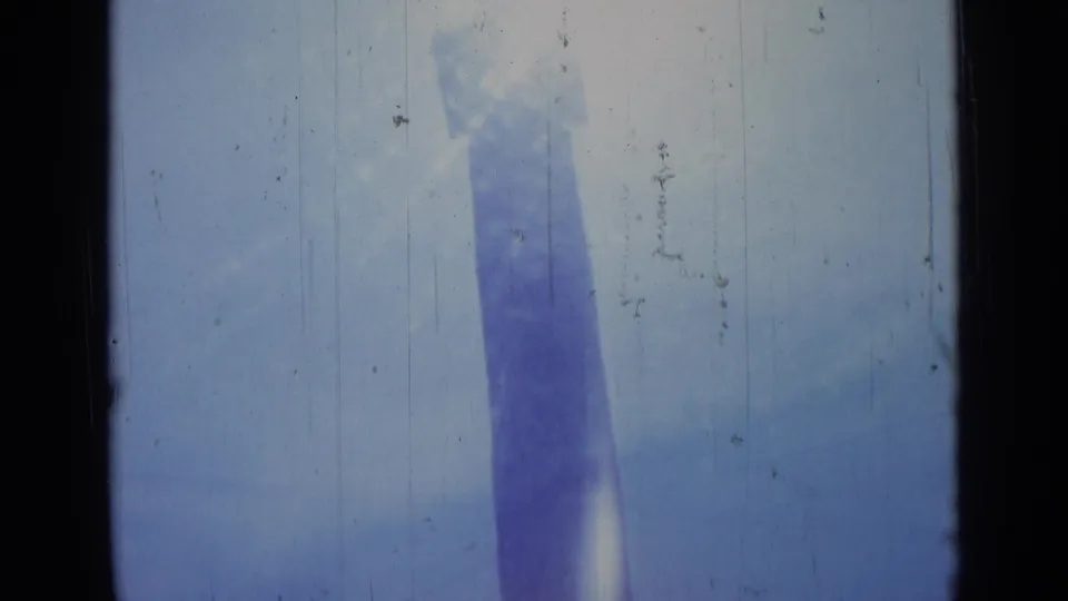 1962 Rome travel frame showing the obelisk more narrowly framed, with blue haze, sun wash, and dark gate edges from the 8mm scan.