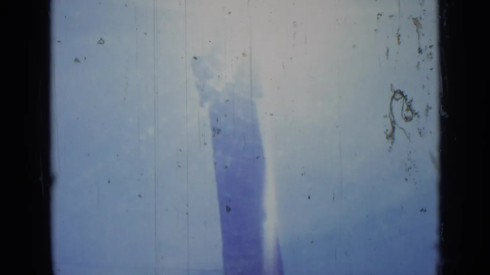 1962 Rome 8mm frame where the obelisk leans in the handheld composition beneath a washed sky, with dust, scratches, and light leak texture.