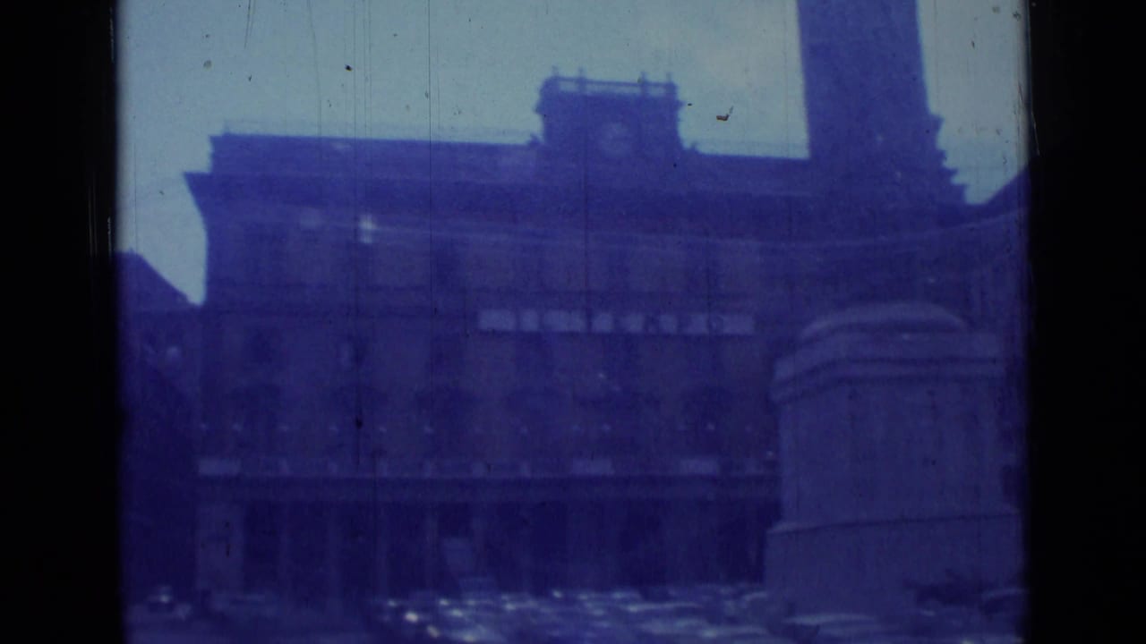 Blue-tinted view of a clock-tower building and street seen through dark film borders.