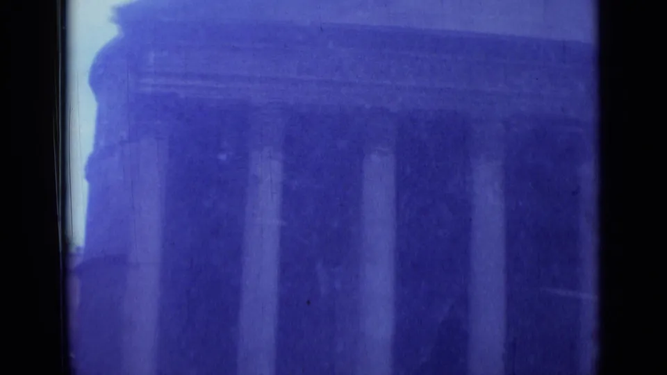 A columned exterior in Rome fills the lower frame, with heavy blue color shift, soft focus, and visible film wear from the 8mm scan.