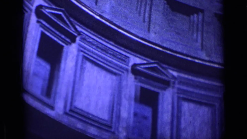 Angled 1962 Rome architectural detail with stone molding, recessed panels, and shadowed facade elements in blue-tinted 8mm footage.