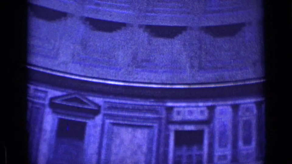 Blue-tinted 1962 Rome 8mm frame showing decorative rectangular wall panels, a dark doorway, and the underside of a circular ceiling.