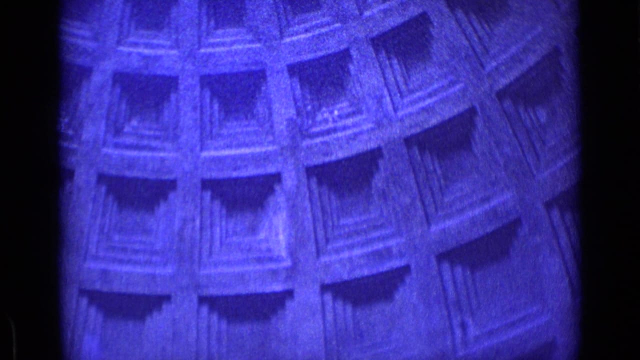 Close 8mm frame of a blue-purple architectural surface in the Rome home-movie clip, showing repeated recessed rectangular details.