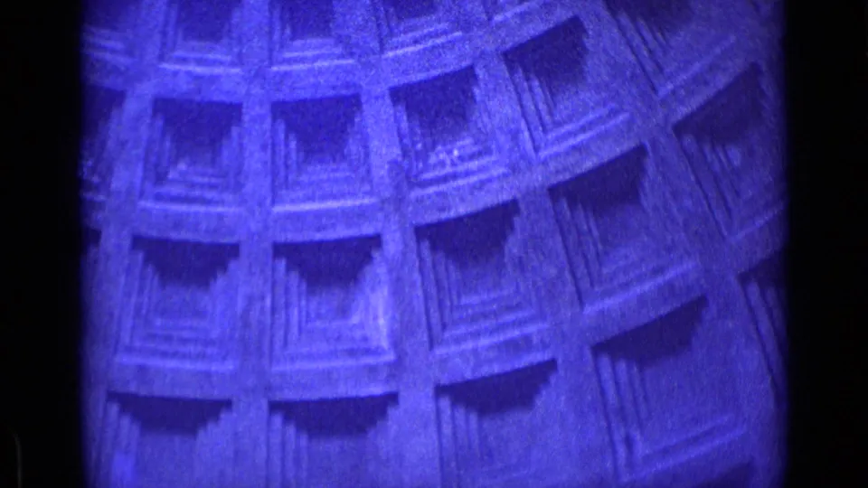 Close 8mm frame of a blue-purple architectural surface in the Rome home-movie clip, showing repeated recessed rectangular details.