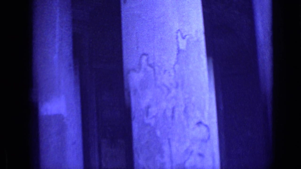 Blue-tinted view of massive stone columns and carved wall surfaces.