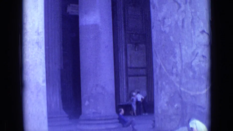 1962 Rome travel frame showing visitors near the base of huge columns beside weathered carved stonework.