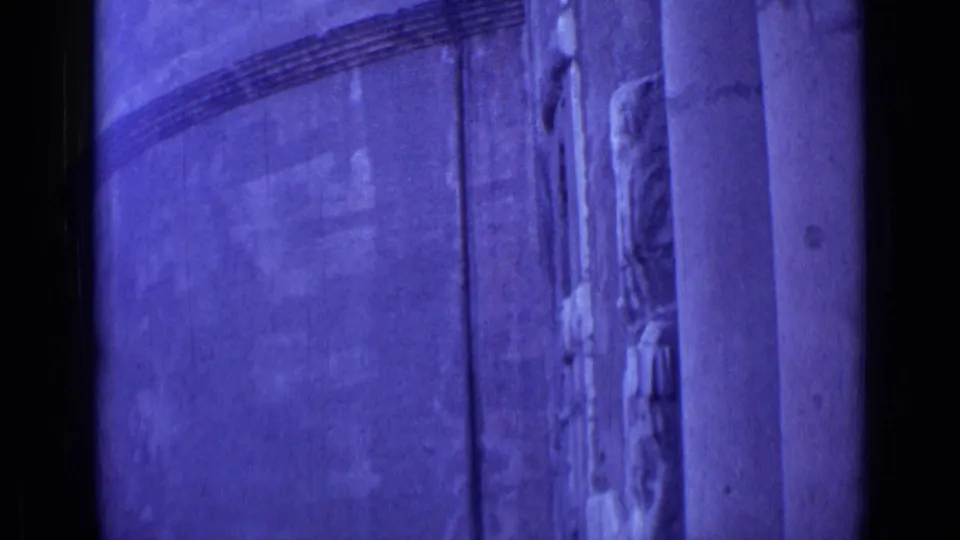 1962 Rome 8mm frame showing a purple-tinted building surface with columns, wall banding, and partial decorative detail.