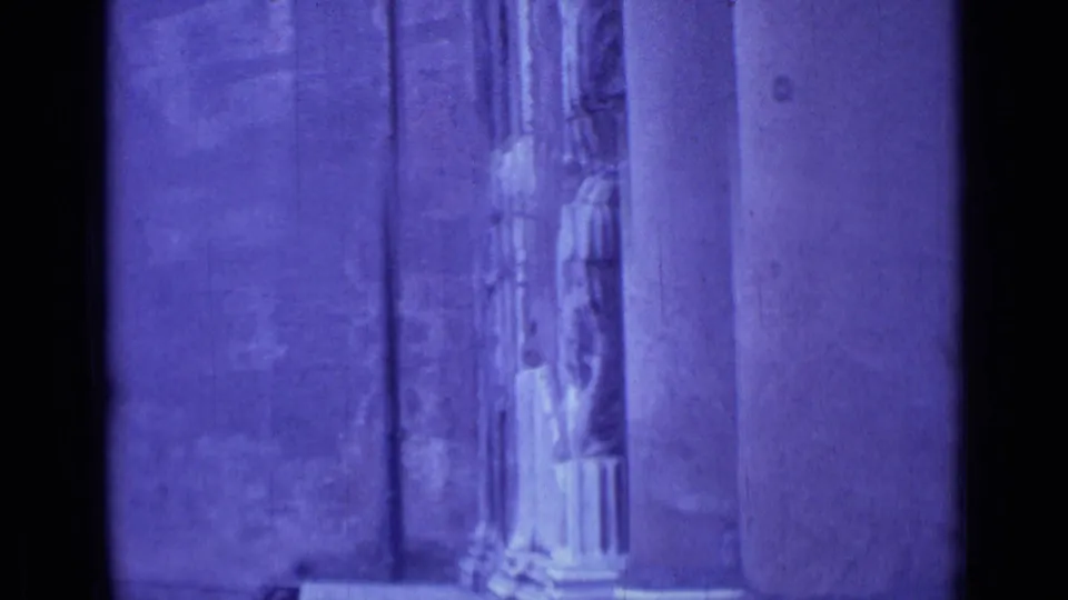 1962 Rome 8mm frame showing purple-tinted stone pilasters and carved religious entrance details, partly obscured by dark film edge shadows.