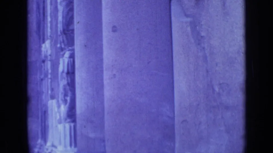 Purple-blue 1962 Rome 8mm frame with tall stone pilasters, carved doorway detail, and heavy vertical film-edge shadow.