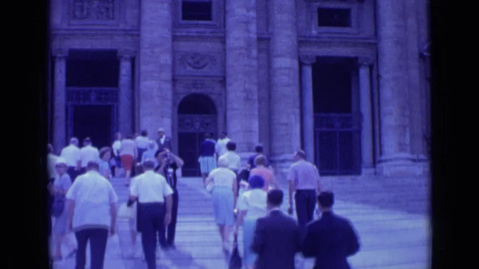 Handheld 8mm view of tourists climbing wide steps beneath tall columns and arched openings in Rome.