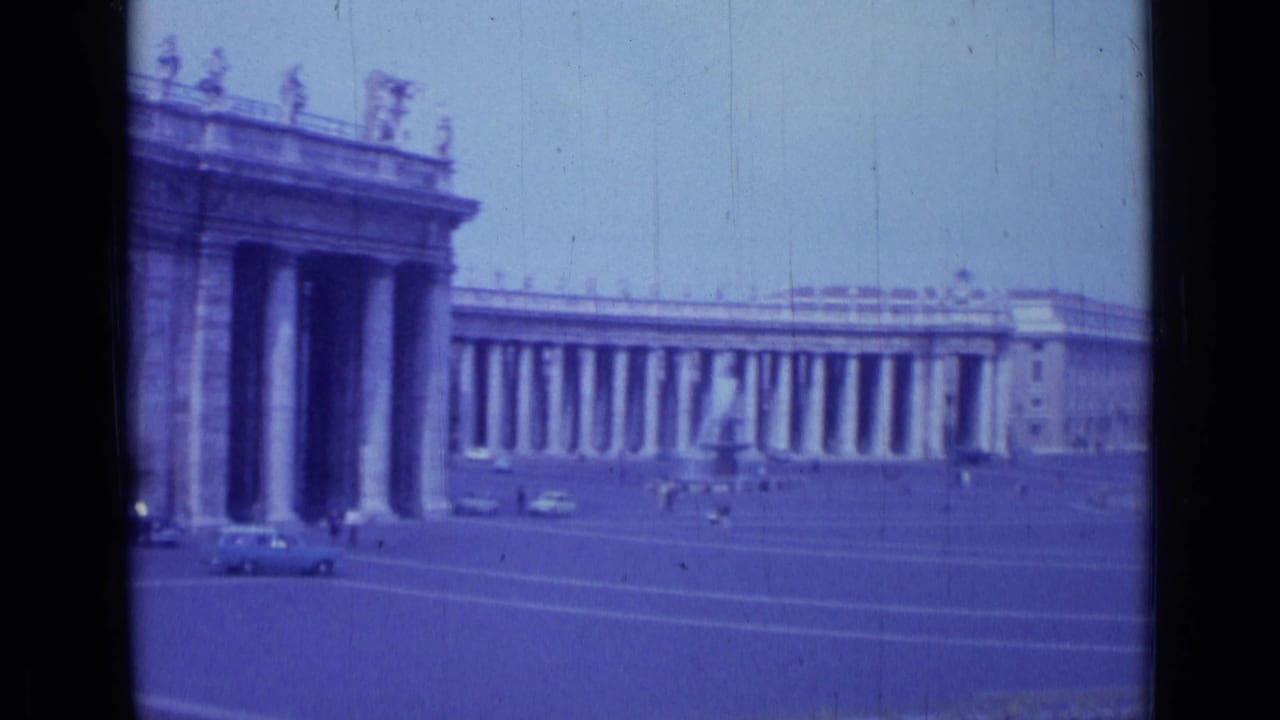 1962 8mm view of St. Peter's Square in Rome, showing the colonnade, open plaza, passing cars, and small distant figures.