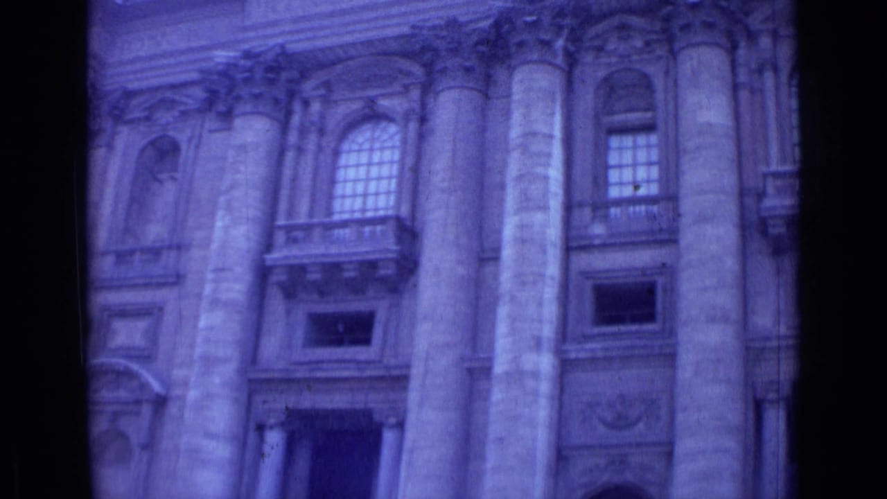 Closer facade view with large columns, arched windows, balconies, and a dark central film divider.