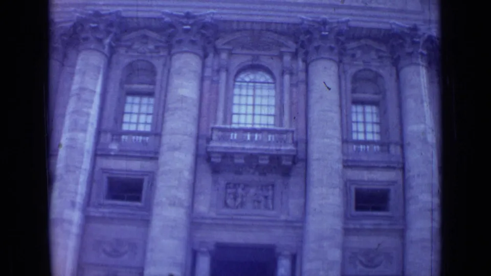 1962 Rome frame of a monumental facade with tall stone columns, arched windows, carved panels, and handheld framing.