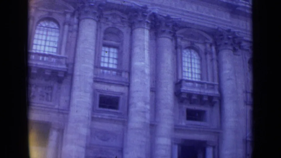 Handheld 8mm view in Rome showing columns, upper windows, balconies, and ornate stone facade details.