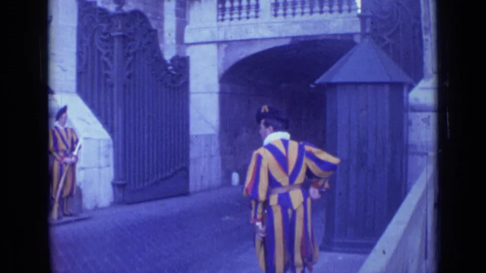 1962 Rome frame with one Swiss Guard seen from behind and another standing at attention beside the iron gate.