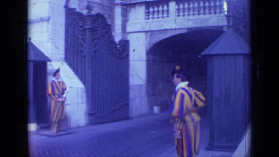 1962 Rome home-movie frame showing a Swiss Guard near a ceremonial entrance with another guard posted by the gate.