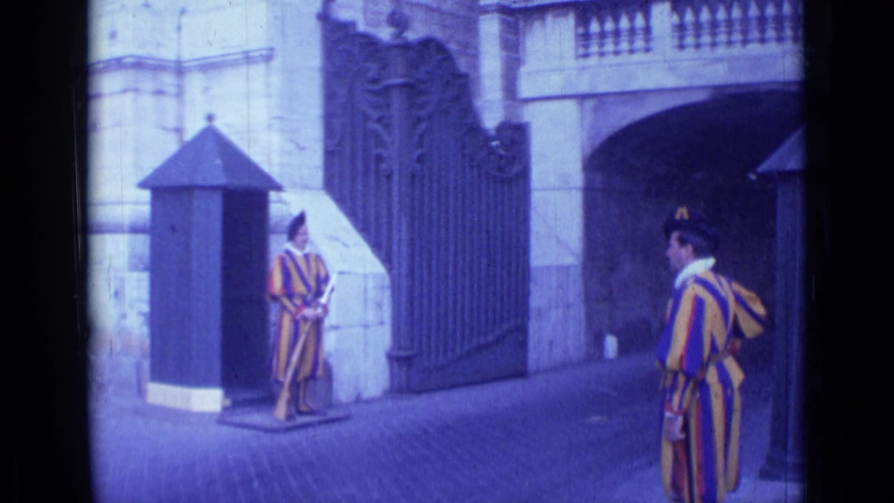 1962 Rome home-movie frame showing Swiss Guard-style ceremonial guards by an ornate gate and small sentry box.