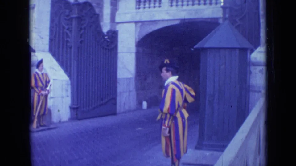 1962 Rome home-movie view of a Swiss Guard-style uniformed figure moving past a posted guard at an ornate gateway.