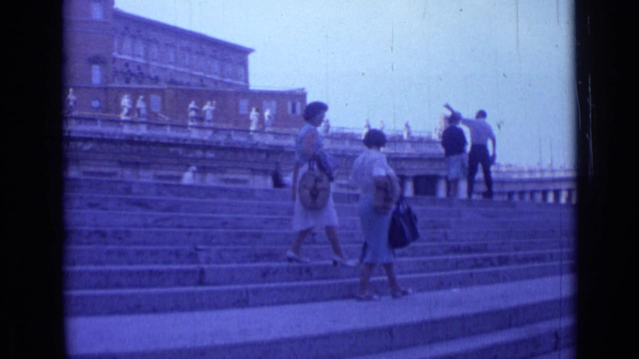 Two women walk on steps as visitors stand and look near the upper terrace.