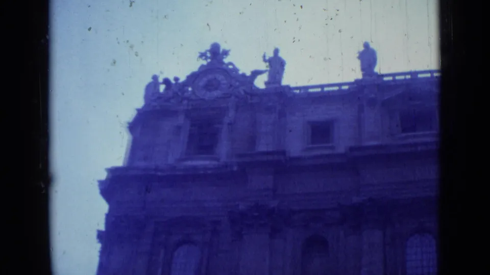 The final frame looks upward at the ornate upper facade of the Rome building, with sculptural figures along the roofline.